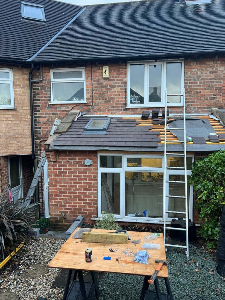 This is a photo of a roof extension that is having new roof tiles installed. This is a photo taken from the roof ridge looking down a tiled pitched roof on to a flat roof. Works carried out by Crawley Roofing Repairs