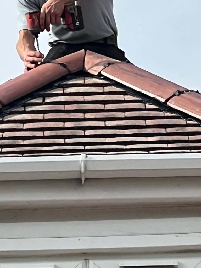 This is a photo of one of the operatives of Crawley Roofing Repairs installing new ridge tiles