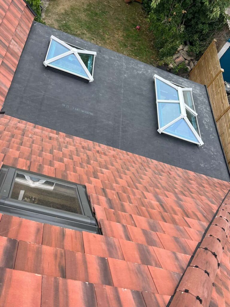 This is a photo taken from the roof ridge looking down a tiled pitched roof on to a flat roof. Works carried out by Crawley Roofing Repairs